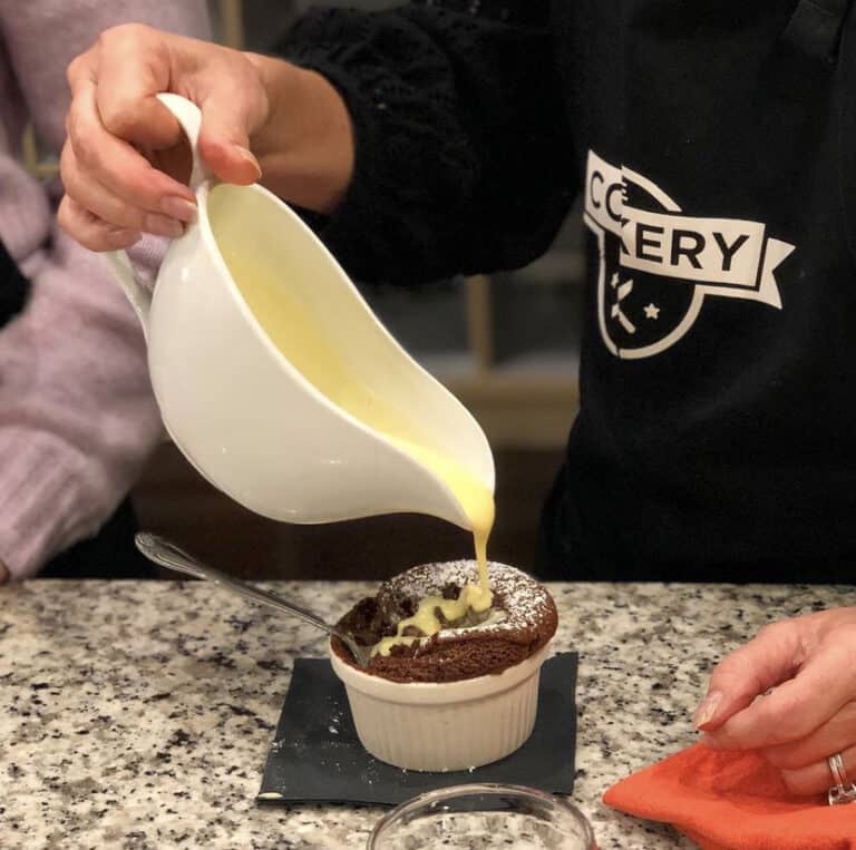 Custard is being added to a ramekin at a cooking class Dallas.